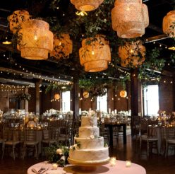 Bamboo pendant light and greenery installation hung over wedding cake table