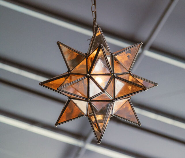 A 3D star shaped pendant light created with antique bronze framing and mercury-style glass